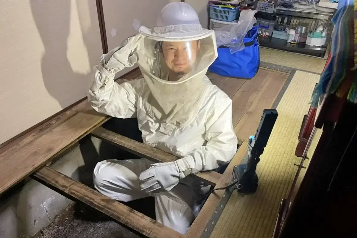床下の閉所にできた蜂の巣を駆除する作業員